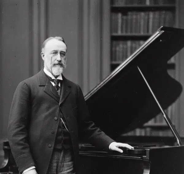 IMAGEN DE THEODORE DUBOIS PARADO JUNTO A UN PIANO